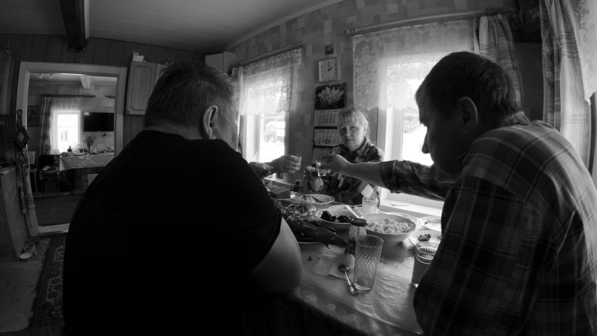 Monochrome scene of family toasting indoors around a table, evoking warmth and togetherness.